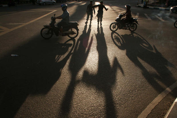 The shadows of Indonesian soldiers directing traffic are cast by the afternoon sun  