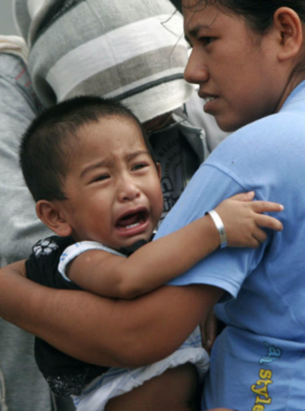 A boy cries as he is carried by his mother 