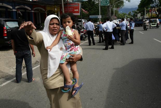 An Acehnese woman with a child tries to stop a car  