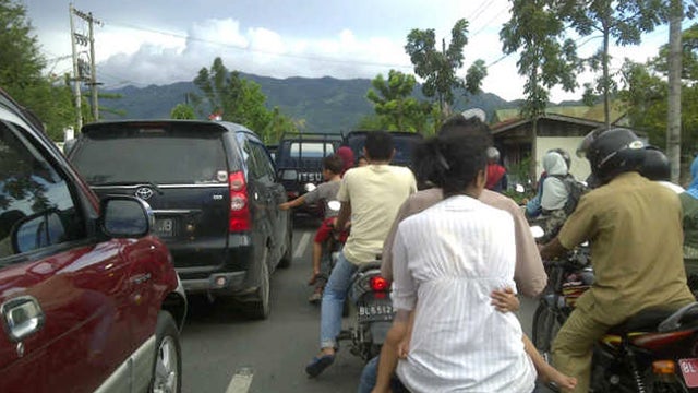 Residents on motorbikes and cars evacuate to higher ground after a strong earthquake was felt in Banda Aceh 