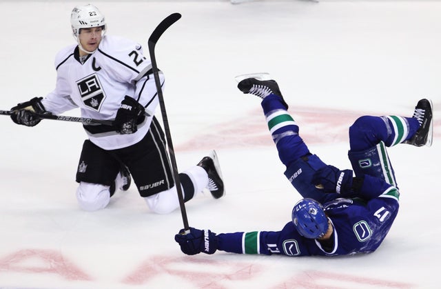Ryan Kesler falls to the ice after a collision with Dustin Brown  