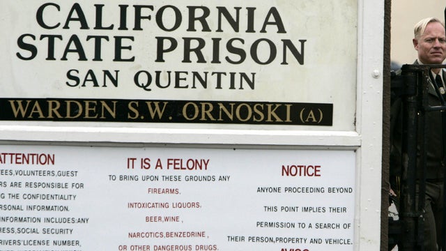 A police officer watches over a fence at the entrance of San Quentin State Prison during a protest against the execution of death row inmate Stanley "Tookie" Williams in San Quentin, Calif., Dec. 12, 2005. 