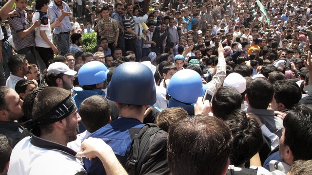 In this April 23, 2012 photo, Syrian protestors gather around U.N. observers during their visit in Douma near the capital of Damascus, Syria.  