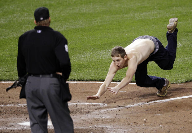 A fan dives into home plate in front of umpire Jeff Kellogg 