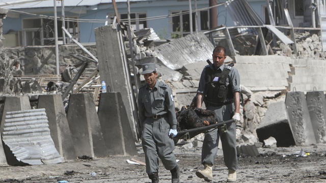 Afghan police carry a body out of the Green Village housing compound 