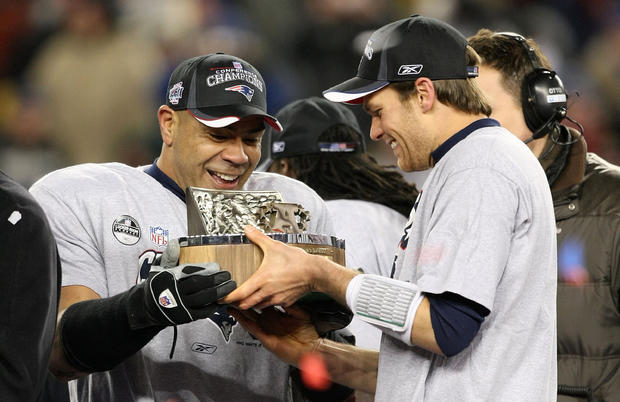 Junior Seau (55) and Tom Brady (12) of the New England Patriots celebrate with the Lamar Hunt AFC Championship trophy  