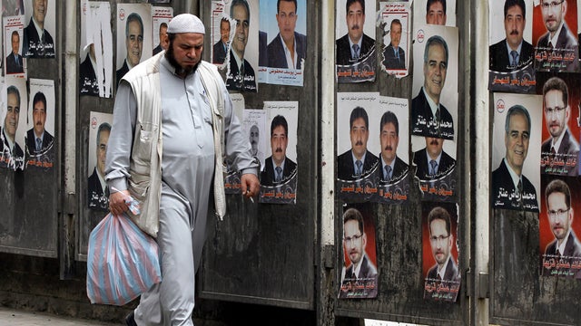 Syrian man walks past campaign posters for the upcoming parliamentary election 