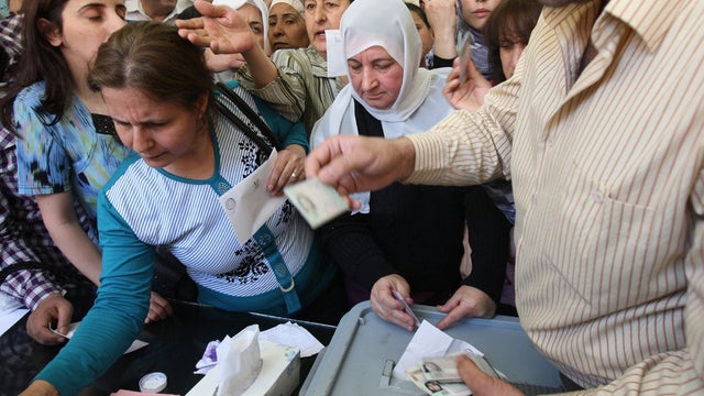 Syrian women have their identification checked before casting their vote in the parliamentary elections 