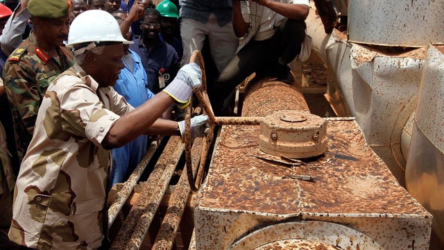 Sudanese Oil Minister Awad Ahmad al-Jaz turns the tap to start pumping oil again from the war-damaged Heglig oil facility May 2, 2012, 12 days after occupying South Sudanese troops left the area. 