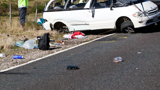 Police officers examine the scene of a minivan crash near Turangi, New Zealand, May 12, 2012. 