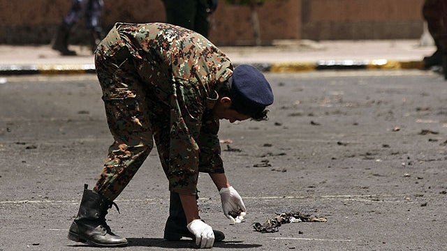 A policeman collects evidence at the site of a suicide bomb attack at a parade square in Sanaa, Yemen, May 21, 2012.  
