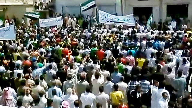 In this image made from amateur video released by the Shaam News Network and accessed Wednesday, May 23, 2012, purports to show Syrians chanting slogans during a demonstration in Idlib, Syria. 