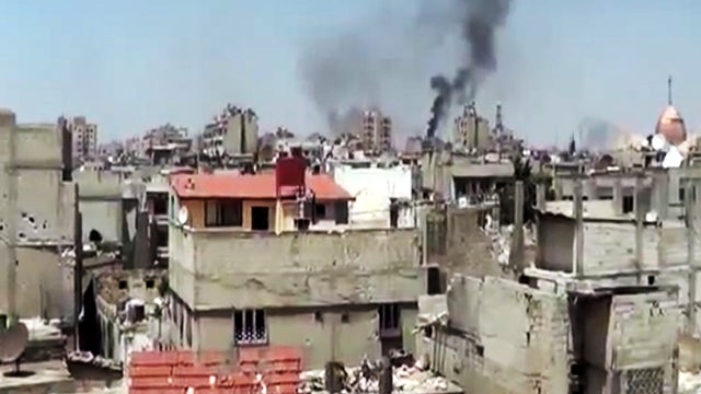 This image made from amateur video released by the Shaam News Network May 28, 2012, purports to show black smoke rising from buildings in Homs, Syria. 