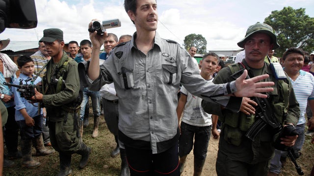 French journalist Romeo Langlois, center, is escorted by rebels of the Revolutionary Armed Forces of Colombia, FARC, upon their arrival to San Isidro, southern Colombia, Wednesday, May 30, 2012.  