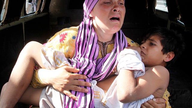 A Syrian woman cries as she carries her injured son, who was shot in the hand by a Syrian border guard when they were crossing a river from Syria to Lebanon, at the northern Lebanese-Syrian border town of Wadi Khaled, Lebanon, May 30, 2012. 