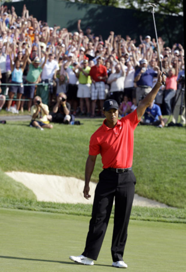 Tiger Woods raises his putter after making a birdie putt  