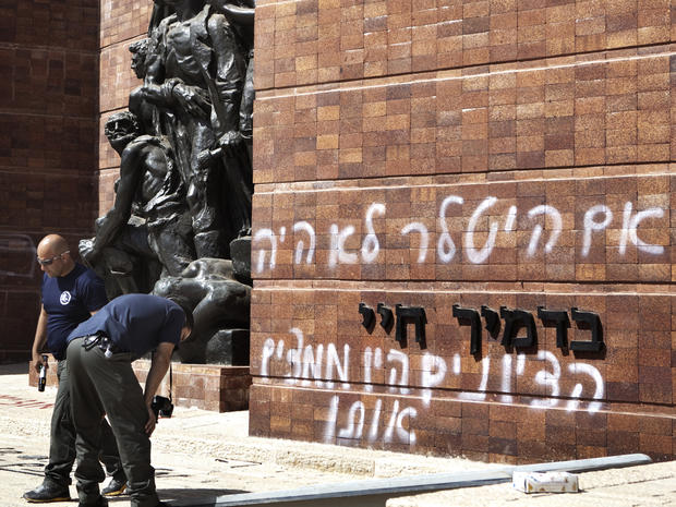 Police inspect anti-Zionist graffitit on the Yad Vashem memorial 