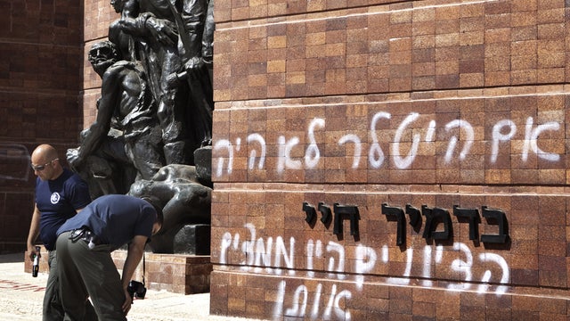 Police inspect anti-Zionist graffitit on the Yad Vashem memorial 