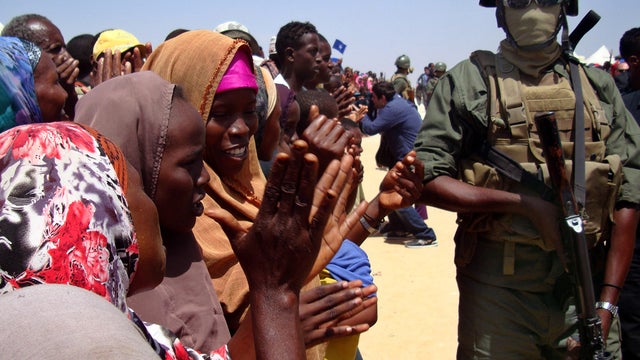Somali women, residents of Mogadishu, cheer as an armed security officer keeps watch March 6, 2012, after a Turkish Airlines aircraft arrived on its maiden commercial flight into the war-torn Somalia capital. 