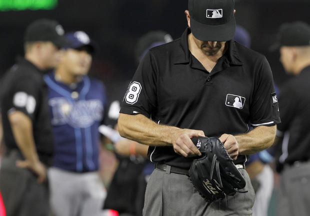 Umpire Chris Guccione leaves with the glove of Tampa Bay Rays relief pitcher Joel Peralta  