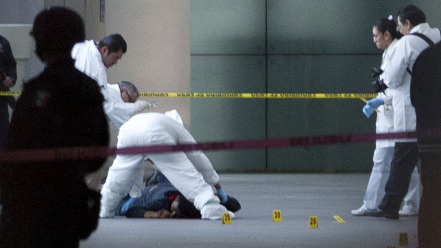 A forensic team inspect a body at Mexico City's International Airport Terminal 2, Monday, June 25, 2012. 