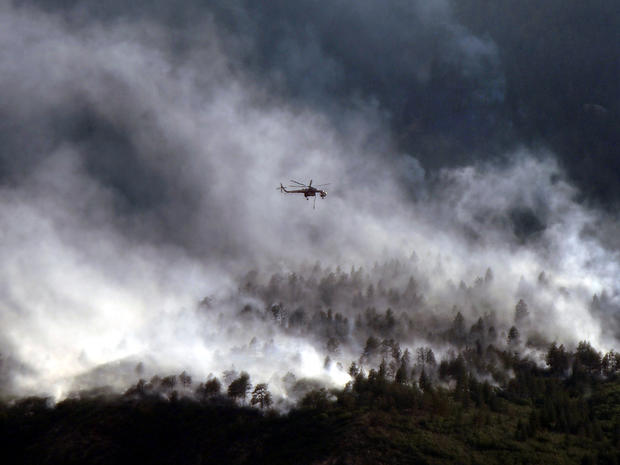 A helicopter flies over the Waldo Canyon fire as it continues to burn June 27, 2012, in Colorado Springs, Colo. 