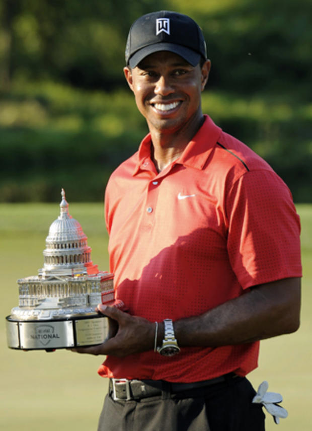 Tiger Woods poses with the trophy on the 18th green 