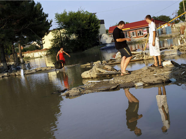 People walk along a flooded street in Krimsk, about 1,200 kilometers (750 miles) south of Moscow, Sunday July 8, 2012. 