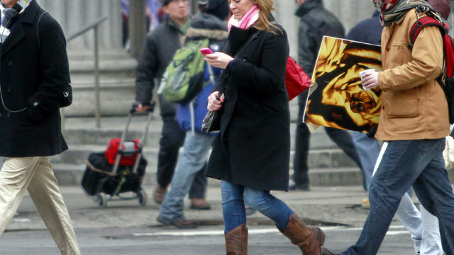 A pedestrian looks at her cell phone while crossing the street in New York City. 