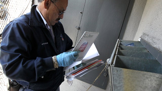U.S. Postal Service letter carrier Juan Padilla puts letters into a mailbox as he walks his delivery route Dec. 5, 2011, in San Francisco. 