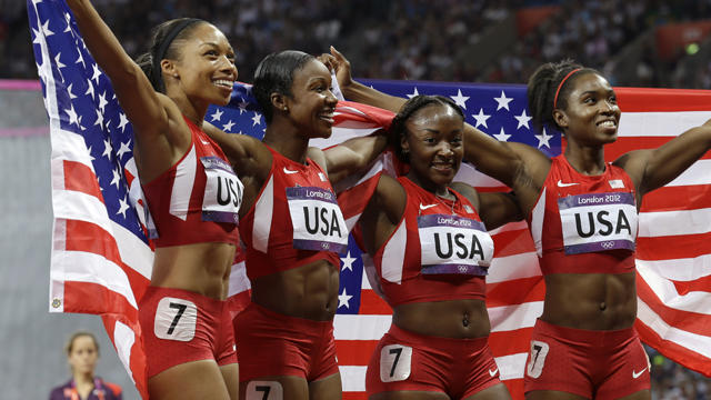 U.S. women's 4 x 100-meter relay team members pose with American flag after winning the gold medal 