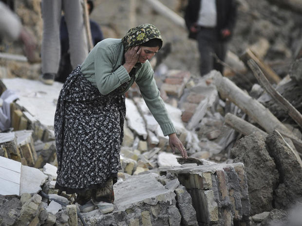 A victim of Saturday's earthquakes touches ruins of buildings 