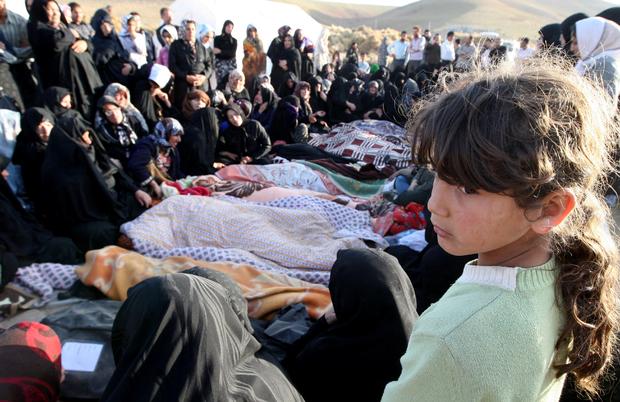 An Iranian girl mourns over the covered bodies of loved ones in Bajebaj village 