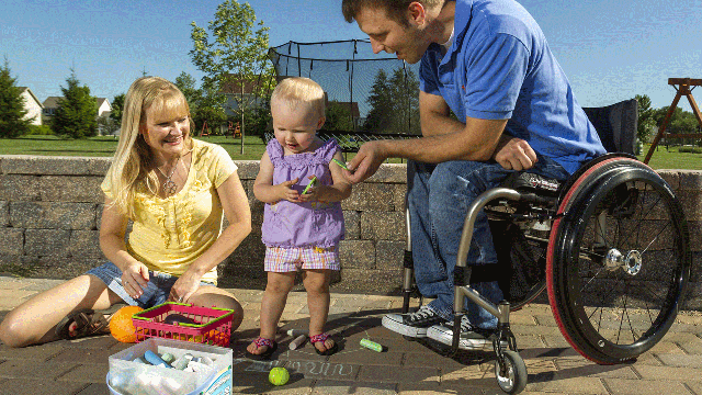 In this photo taken Aug. 6, 2012, Brenda and Chuck Isaacson play in their back yard with their 16-month old daughter, in Sun Prairie, Wis.  