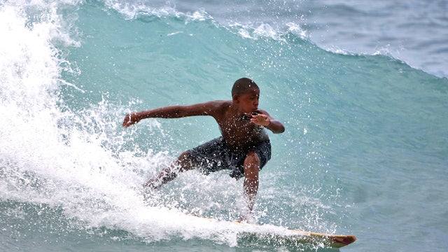 A boy surfs a wave at a beach in Barahona, Dominican Republic, before the anticipated arrival of Tropical Storm Isaac, Thursday, Aug. 23, 2012. 