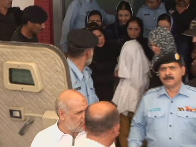 A Christian Pakistani girl, covered in a white cloth, is ushered into a police vehicle 