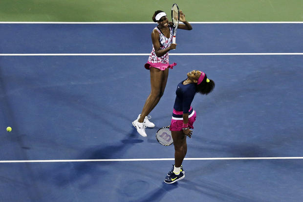 Venus Williams, left, and Serena Williams react as they miss a point  