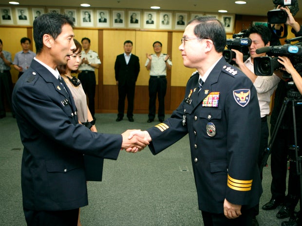 South Korean traffic cop Kim Hyun-cheol, left, shakes hands with a commissioner of the Busan Police Agency during his special promotion ceremony in Busan, South Korea, Aug. 31, 2012, in this photo released by the Busan Police Agency. 