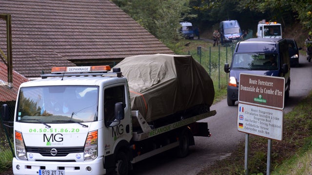 A tow truck escorted by French gendarmes on the 'Combe d'Ire' road carries the car in which three people were shot dead 
