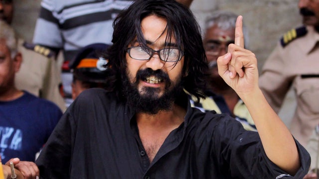 Indian political cartoonist Aseem Trivedi gestures after he is arrested by the police on charges of mocking the Indian constitution in his drawings, in Mumbai, India, Sunday, Sept. 9, 2012. 