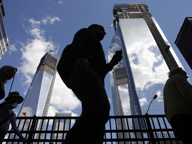 Visitors to the National September 11 Memorial walk below the rising towers 1 World Trade Center, left, and 4 World Trade Center, Monday, Sept. 10, 2012 in New York. Tuesday will mark the eleventh anniversary of the attacks of Sept. 11, 2001. 
