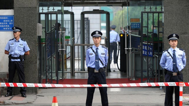 Chinese policemen stand guard outside the Chengdu People's Intermediate court 