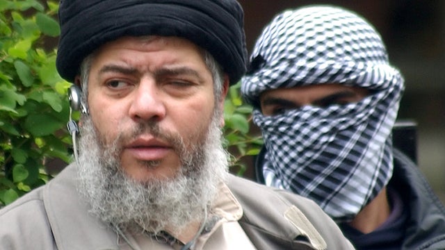 Abu Hamza al-Masri with a masked bodyguard in London on April 30, 2004. 