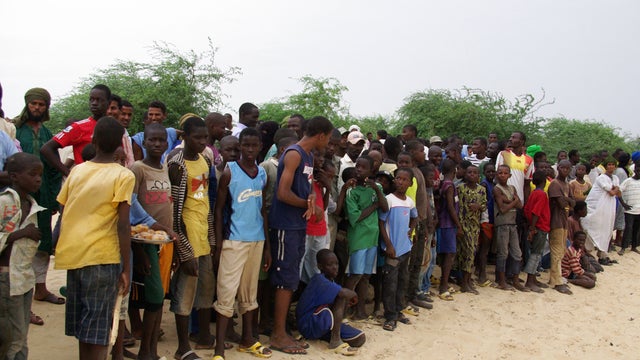 Local residents, including many children, look on as Islamist group prepares to amputate the hand of a young man 