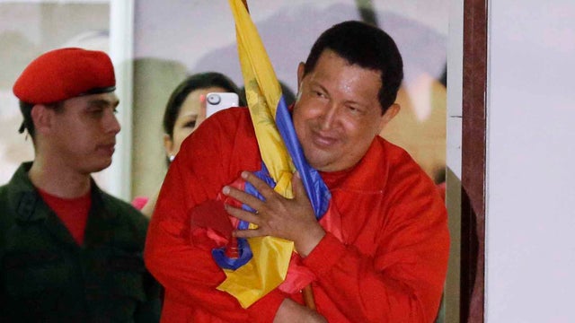Venezuela's president, Hugo Chavez, holds his nation's flag as he greets supporters at the Miraflores presidential palace balcony in Caracas Sunday after winning re-election for third time 