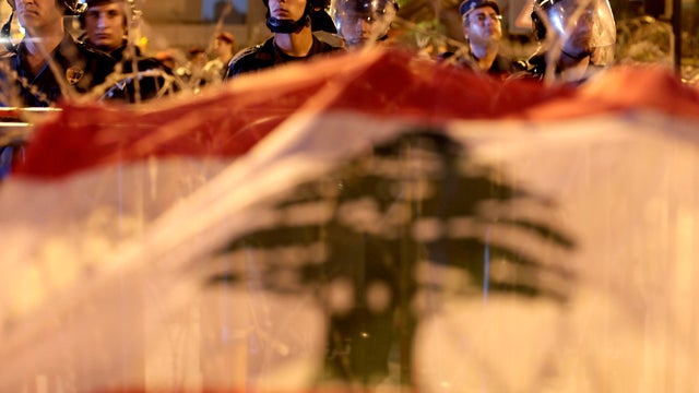 Lebanese riot police stand guard in front of the government palace behind a barbed wire barricade anti-government protesters decorated with the national flag in downtown Beirut Oct. 22, 2012. 