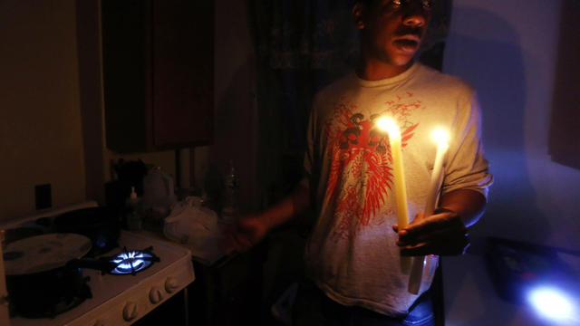 Geronimo Harrison stands in his apartment lit with candles and without power or water as the gas stove burns for heat in the Jacob Riis housing projects in Manhattan's East Village Nov. 1, 2012, in New York. 
