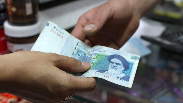 An Iranian woman pays a 20,000 rial banknote to a grocer in Tehran 