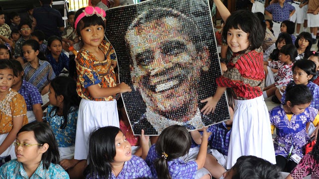 Students hold a poster of President Obama as they watch the U.S. election vote counting at SDN 01 Menteng elementary school 