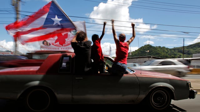 People ride atop a vehicle waving a Puerto Rican flag during elections in San Juan 